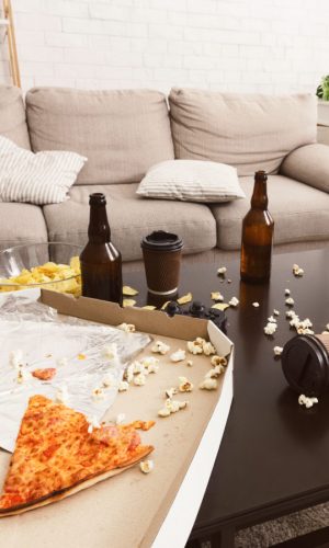 After party interior chaos. Beer bottles, popcorn and pizza After party interior chaos. Beer bottles, popcorn and pizza on table in room